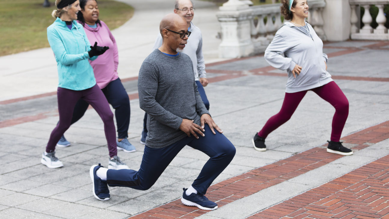 Diverse group of middle-age and older adults stretching in the park