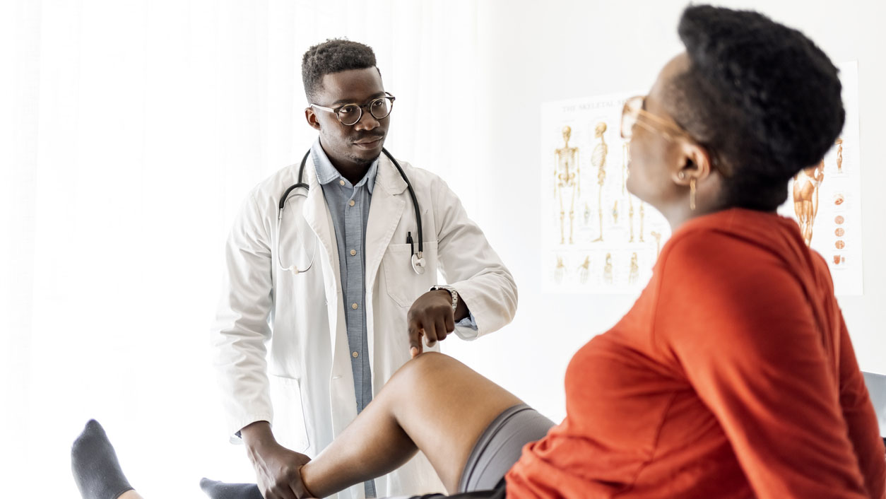 Woman having her knee examined by a doctor Woman discussing her knee pain with her health care provider