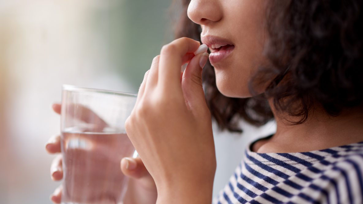 Woman taking medication with water Woman taking medication with water